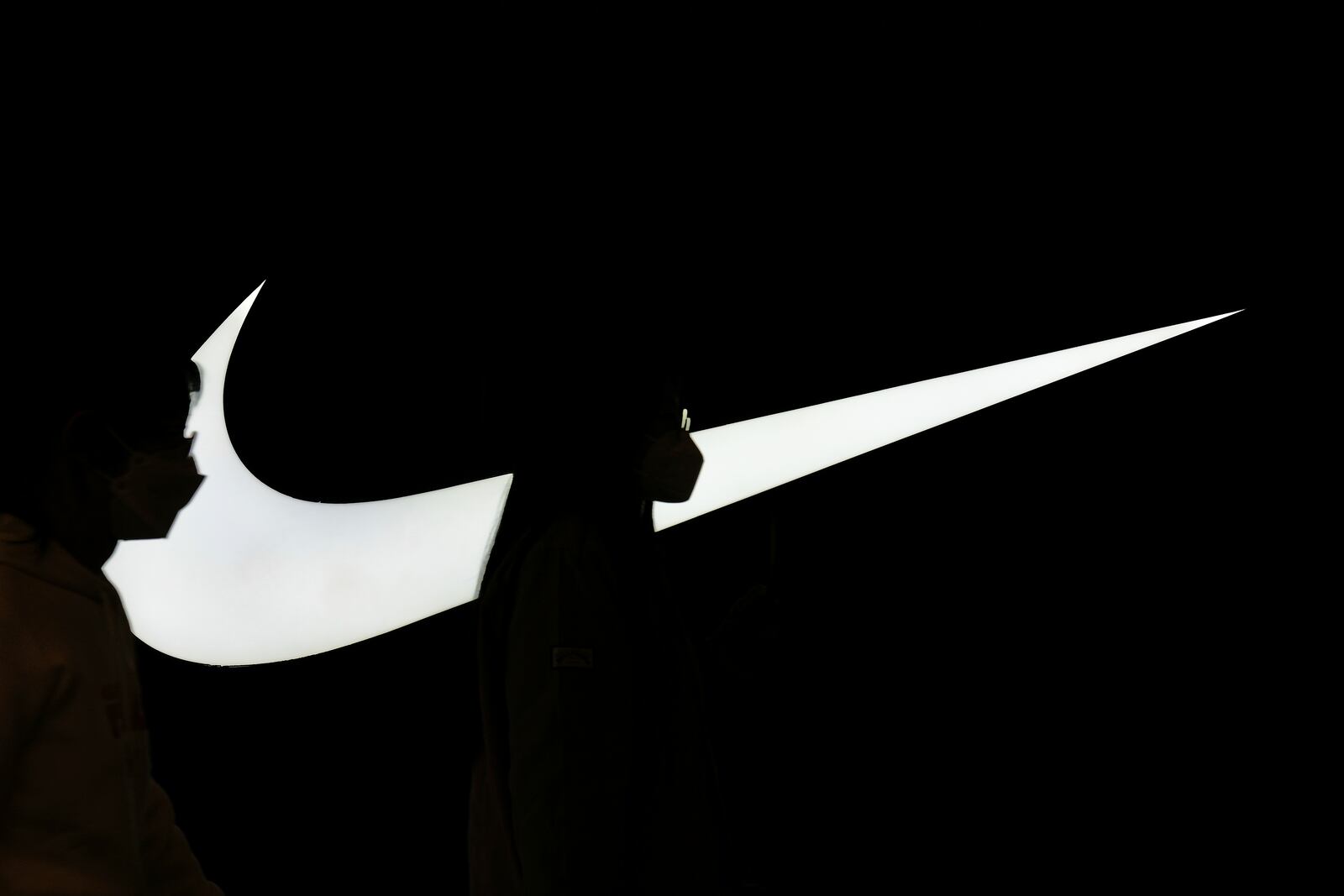Women are silhouetted, as they walk past a Nike signage on display outside the Nike store inside a shopping mall, in Beijing, Tuesday, April 8, 2025. (AP Photo/Andy Wong)
