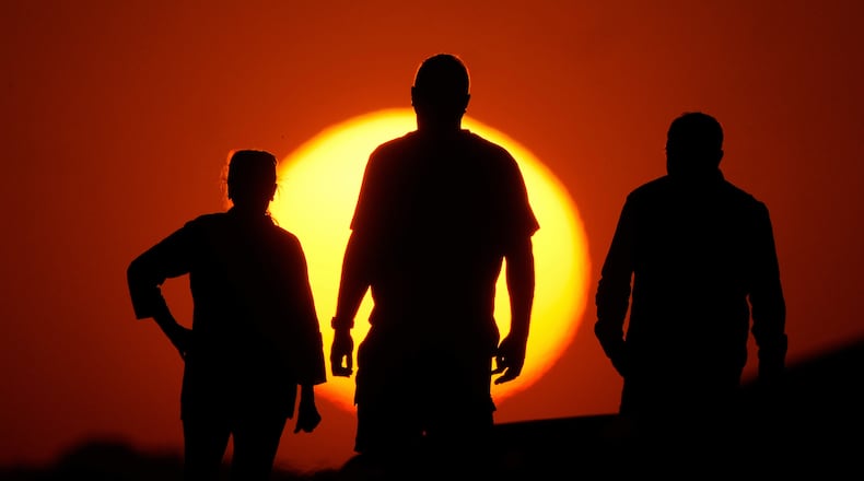 FILE - People watch the sunset from the Liberty Memorial grounds in Kansas City, Mo., May 12, 2025. (AP Photo/Charlie Riedel, File)