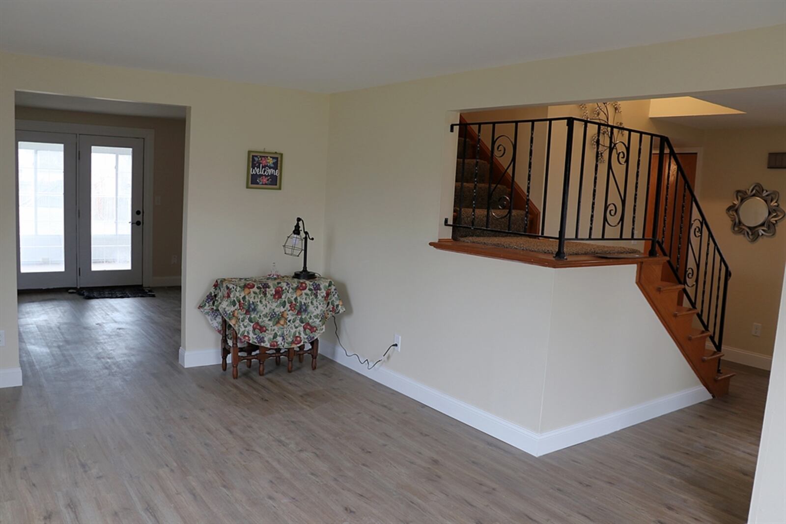 A semi-open staircase with a wrought-iron railing wraps up from the foyer.