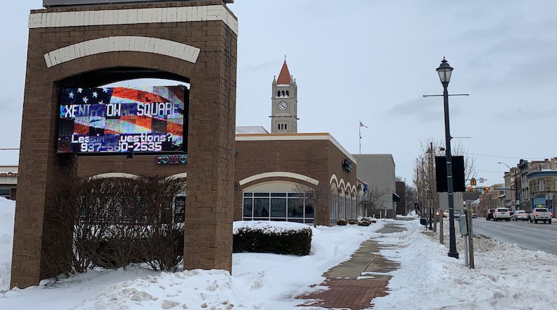 The snowy sign in downtown Xenia marking the city's Towne Square, with the courthouse steeple in the background.