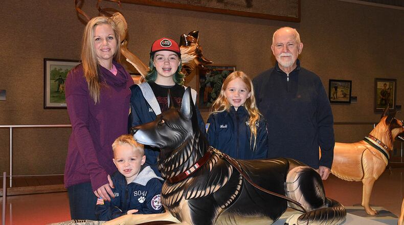 U.S. Air Force veteran Erin Simpson and her children stand with artist James Mellick at the Canine Warriors Exhibit at the National Museum of the U.S. Air Force Nov. 29. Mellick sculpted military working dog Robson L096 to represent the problem of veteran suicides. Retired Tech. Sgt. David Simpson, former military working dog handler of Robson, took his own life in 2017 having Lyme disease and post-traumatic stress disorder. (U.S. Air Force photo/Ken LaRock)