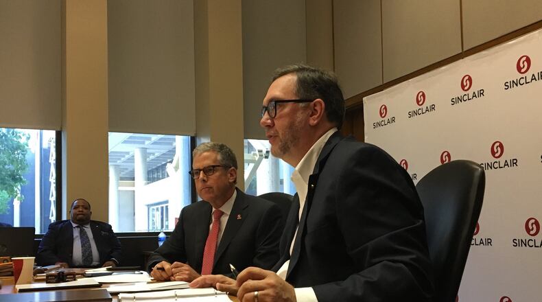 Sinclair board of trustees chairman Rob Connelly, left, sits with Sinclair president Steve Johnson, right, at a board meeting on Monday. Trustees approved a tuition increase on this week along with pay raises for faculty and staff.