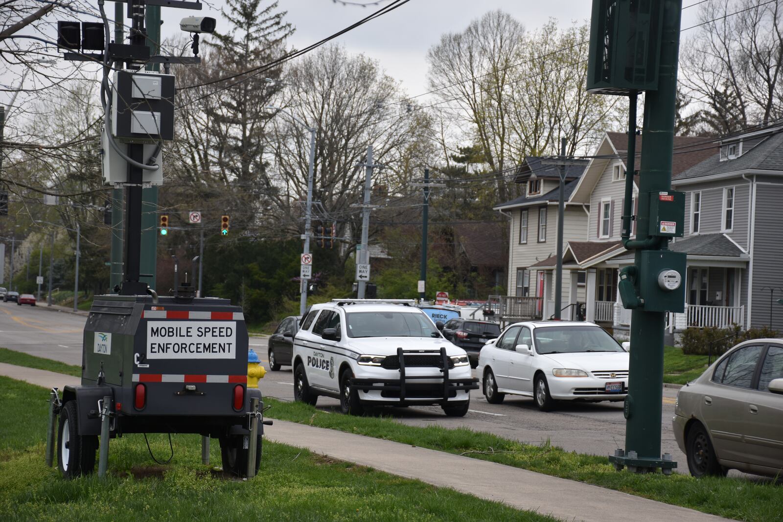 A Dayton Police Department cruiser drives by an automated mobile speed trailer by Belmont High School in Dayton. CORNELIUS FROLIK / STAFF