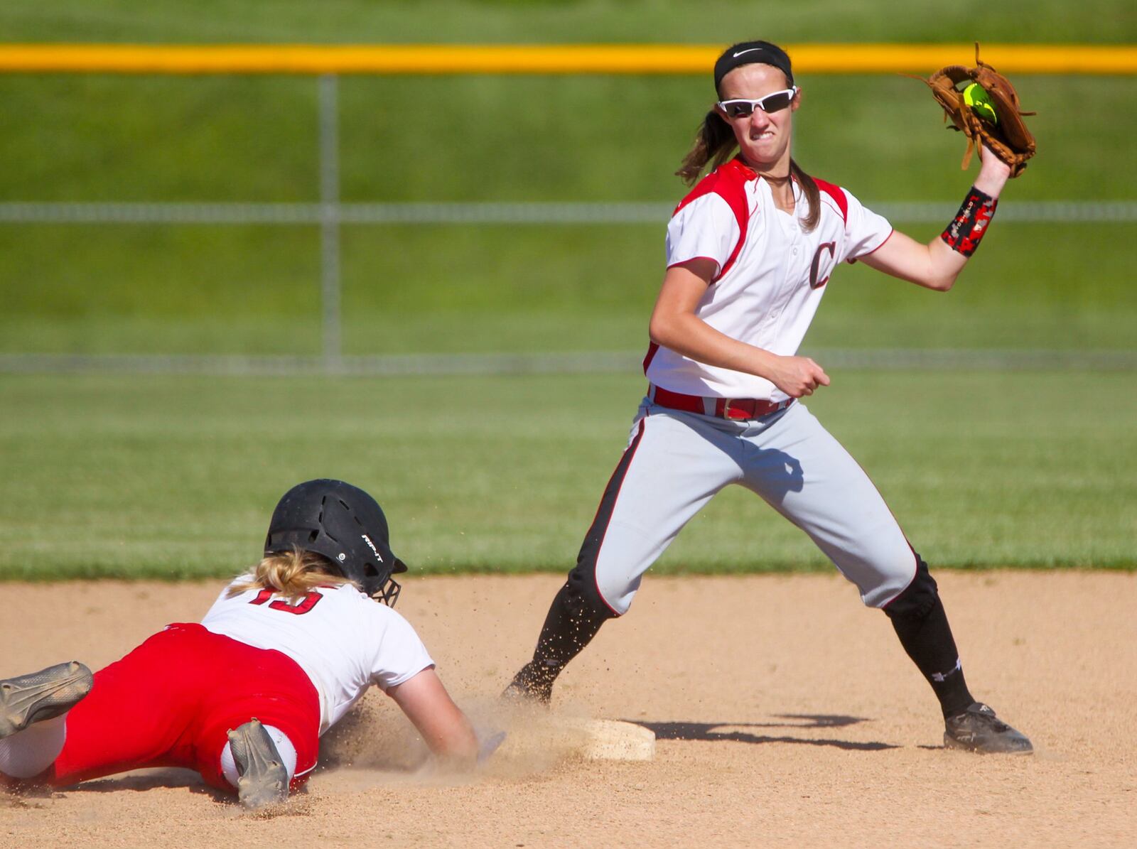 Madison’s Carly Metcalf (15) slides safely back into second base as a throw comes in to Carlisle shortstop Sierra Orth (4) during a Division III sectional final Monday at Fenwick. GREG LYNCH/STAFF