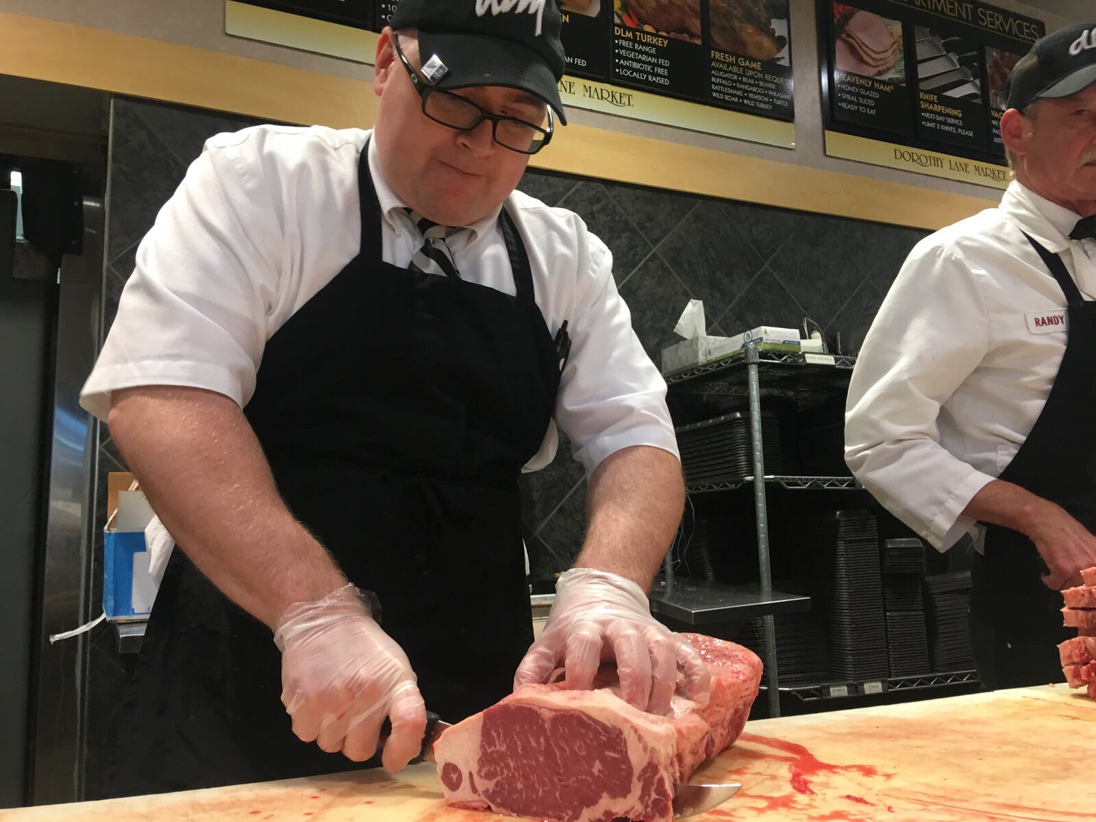 Joe Neuhauser, general manager of the meat department at Dorothy Lane Market in Oakwood, cuts a slab of meat before Memorial Day weekend. KARA DRISCOLL/STAFF