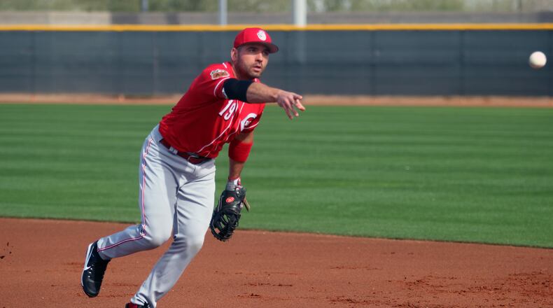 The Reds’ Joey Votto tosses a ball to first during infield drills this week in Goodyear, Ariz. MIKE HARTSOCK/STAFF