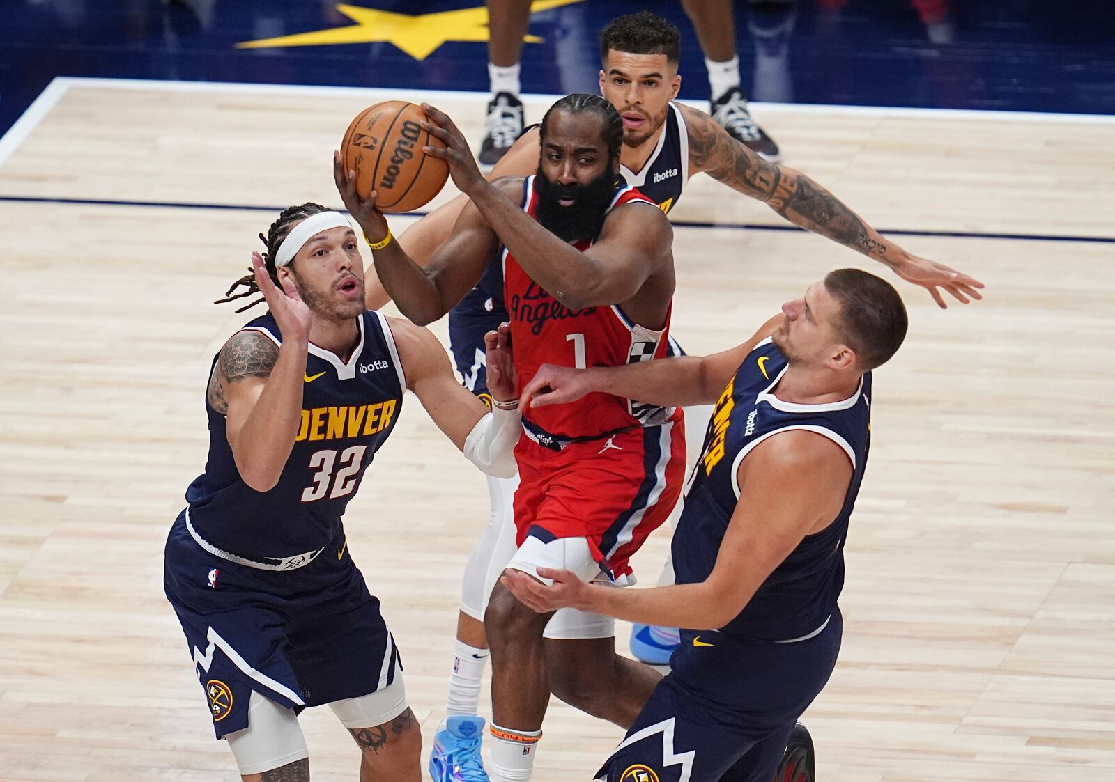 Los Angeles Clippers guard James Harden, center front, looks to pass the ball as Denver Nuggets forward Aaron Gordon (32), forward Michael Porter Jr., center back, and center Nikola Jokic, right, defend in the first half of Game 2 of a first-round NBA playoff series Monday, April 21, 2025, in Denver. (AP Photo/David Zalubowski)