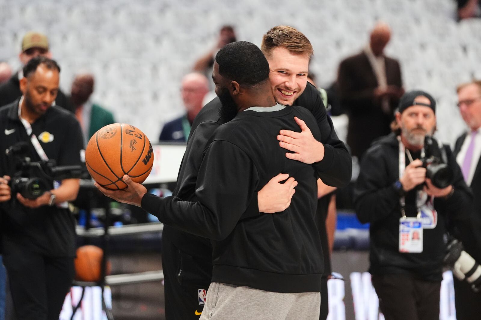 Los Angeles Lakers' Luka Doncic, center right, hugs his former coach, Dallas Mavericks assistant coach God Shammgod, center left, during team warmups before an NBA basketball game in Dallas, Wednesday, April 9, 2025. (AP Photo/LM Otero)