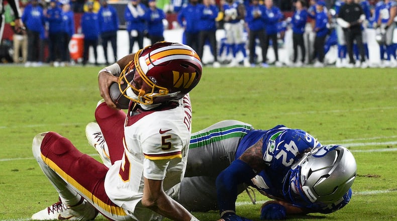 Washington Commanders quarterback Jayden Daniels (5) injures his arm as he is tackled by Seattle Seahawks linebacker Drake Thomas (42) during the second half of an NFL football game, Sunday, Nov. 2, 2025, in Landover, Md. (AP Photo/Nick Wass)