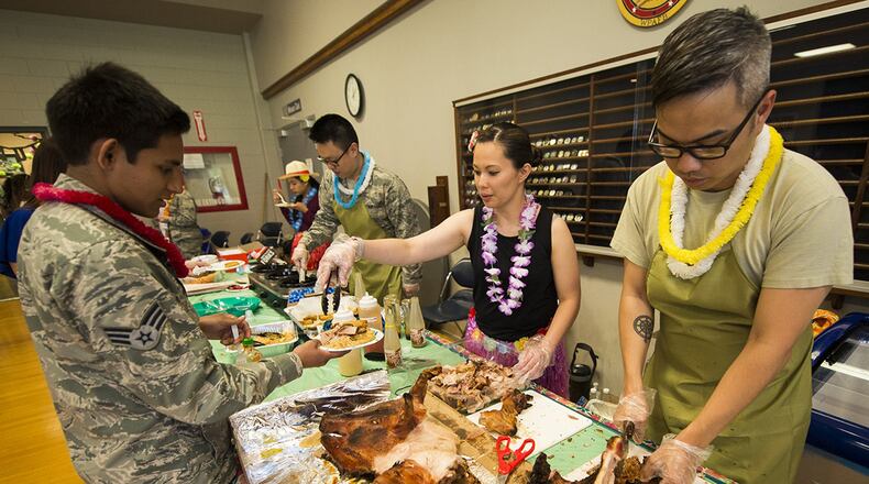 Staff Sgt. Mark Miraflor (right), a medical logistics technician with the 88th Medical Support Squadron cuts up roast pork to serve during a luau event on Wright-Patterson Air Force Base, on May 23. The luau was sponsored by the Asian-American/Pacific Islander Heritage Month committee and was the last of a series of events the committee held during May to celebrate the rich and diverse cultures Asia and the Pacific regions. (U.S. Air Force photo/Jim Varhegyi)