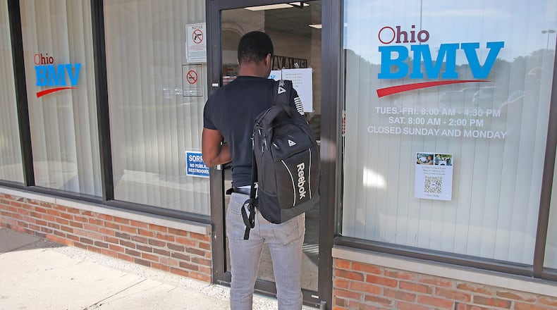 A man reads a sign on the door of the Ohio BMV testing center in the Park Shopping Center on Thursday, Sept. 21, 2023. BILL LACKEY/STAFF