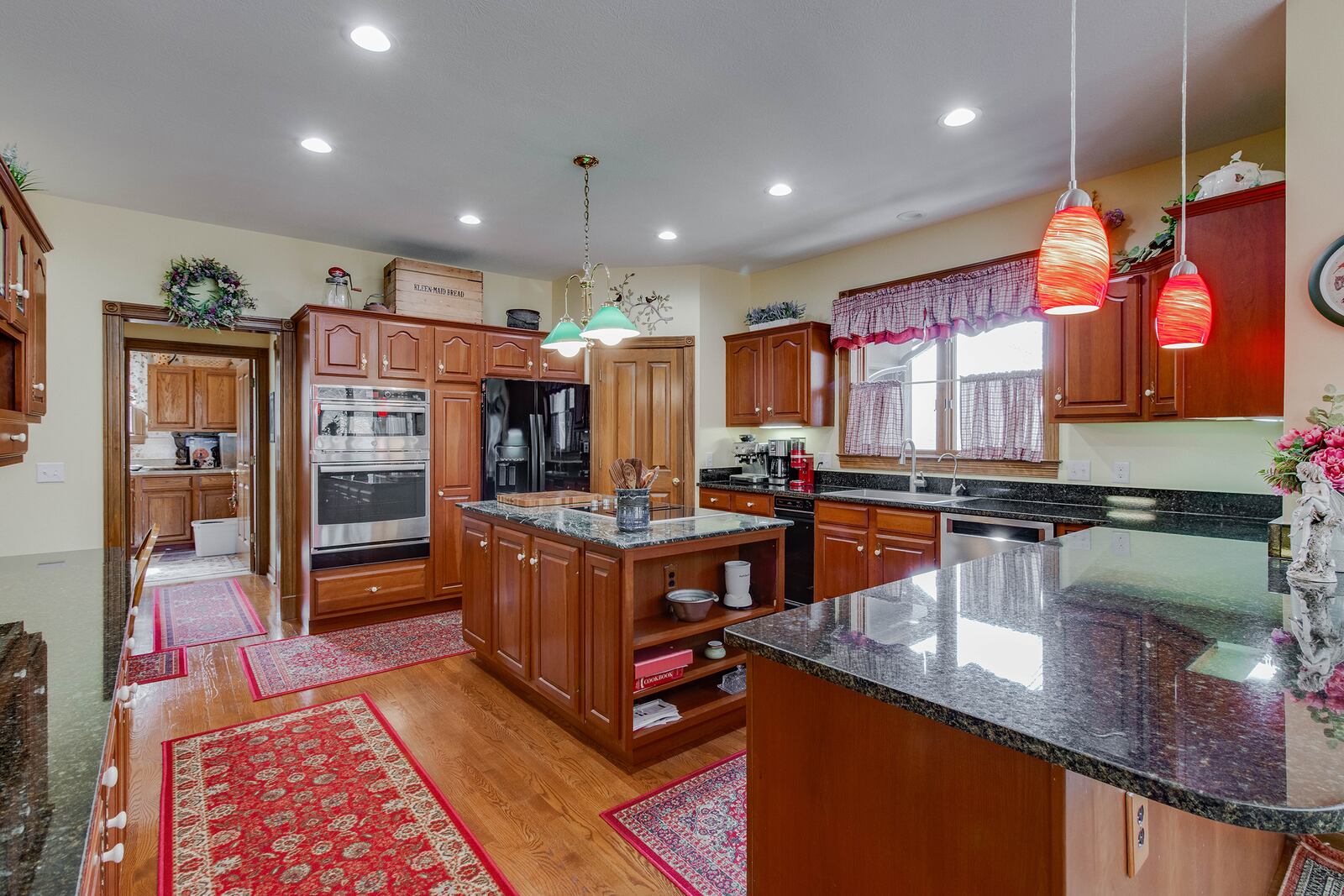 The kitchen has hardwood flooring, custom wood cabinets and appliances including an island cooktop and wall oven.