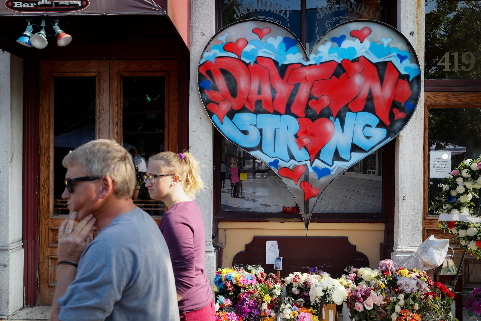 FILE - In this Aug. 7, 2019 file photo, pedestrians pass a makeshift memorial for the slain and injured victims of a mass shooting that occurred in the Oregon District in Dayton, Ohio. (AP Photo/John Minchillo, File)