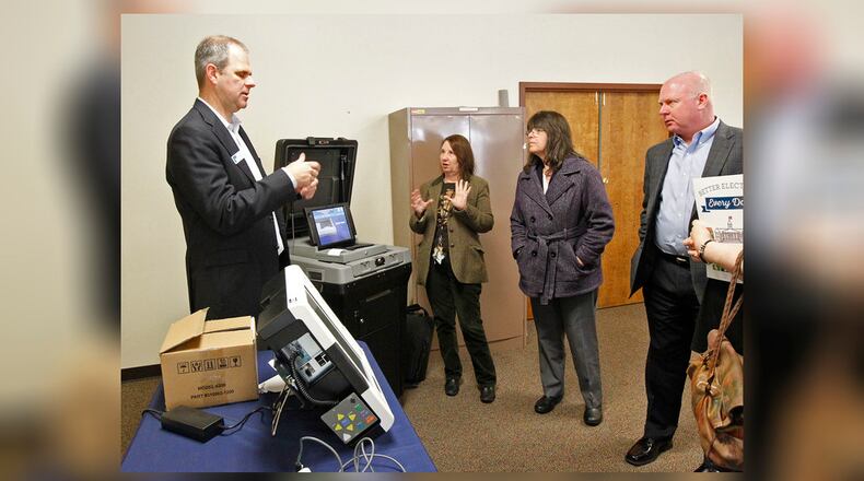 Greene County Board of Elections director Llyn McCoy, center, asks questions to Craig Seibert, regional sales manager, from Election Systems & Software company, left.  Voting machines were demonstrated to the Greene County Board of Elections and County Commissioners. Dominion Voting Systems machines were demonstrated in a later session.    TY GREENLEES / STAFF