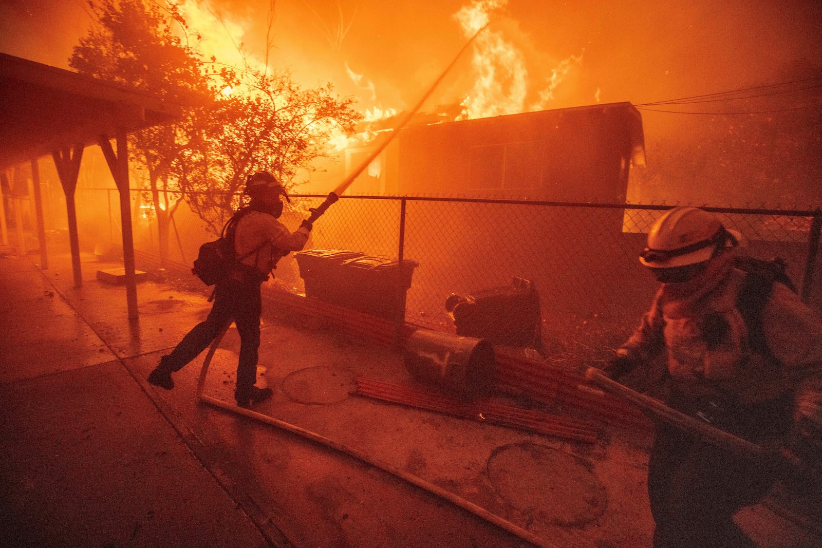 FILE - Firefighters protect a structure as the Eaton Fire advances Jan. 8, 2025, in Altadena, Calif. (AP Photo/Ethan Swope, File)