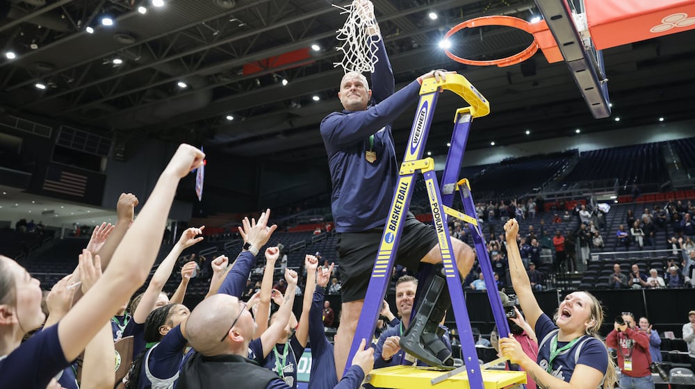 Fairmont coach Jeremy Finn hoists the net after cutting it down following the Firebirds' 61-55 overtime win over Princeton in the Division I state final on Saturday, March 14 at University of Dayton Arena. Finn is in his eighth season at the helm. BRYANT BILLING / STAFF