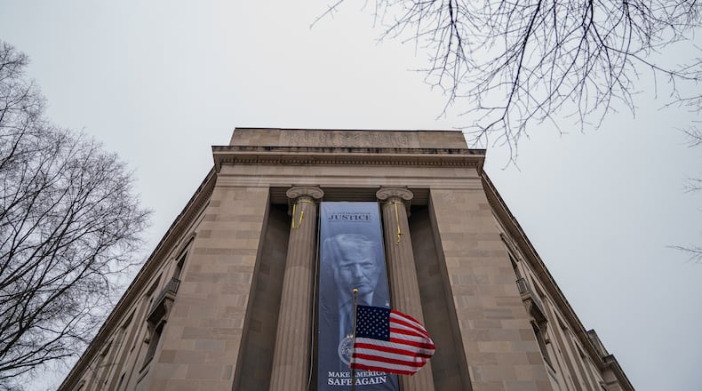 A banner showing President Donald Trump is hung from the Department of Justice, Thursday, Feb. 19, 2026, in Washington. (AP Photo/Allison Robbert)