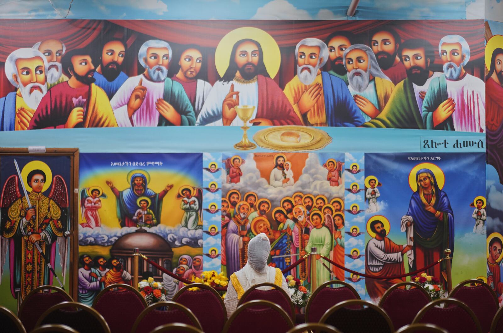 A worshipper kneels before a depiction of "The Last Supper" at Re'ese Adbarat Debre Selam Kidist Mariam Church, an Ethiopian Orthodox Tewahedo church, in Washington, D.C., Saturday, April 5, 2025. (AP Photo/Jessie Wardarski)