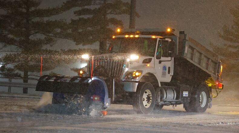 A snow plow cleans off the intersection of Taylorsville Road and Old Troy Pike in Huber Hights Sunday evening. BILL LACKEY/STAFF