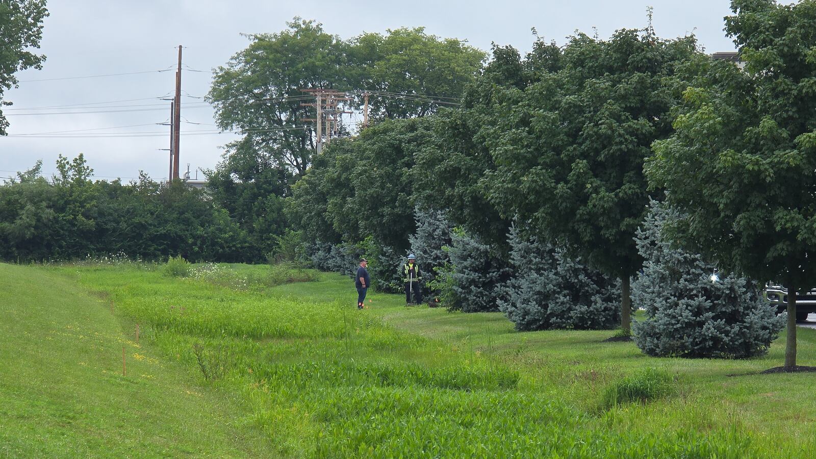 Workers talk near a drainage ditch next to Parker Trutec in PrimeOhio Corporate Park near state Route 41 in Springfield on Thursday, July 31. A water-chemical mix of 1,400 gallons leaked into a drainage ditch that flows into a retention pond on Wednesday night. BRYANT BILLING / STAFF