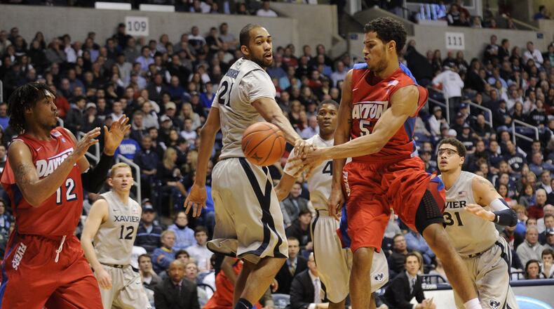Dayton’s Devin Oliver makes a pass to Jalen Robinson in front of Jeff Robinson of Xavier PHOTO ERIK SCHELKUN