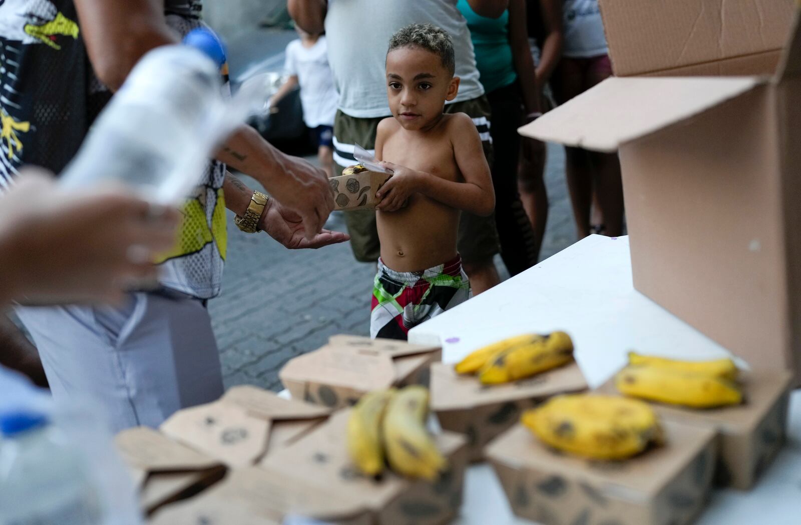 FILE - A boy receives food donated by a social project at the Turano favela, in Rio de Janeiro, June 17, 2024. (AP Photo/Silvia Izquierdo, File)