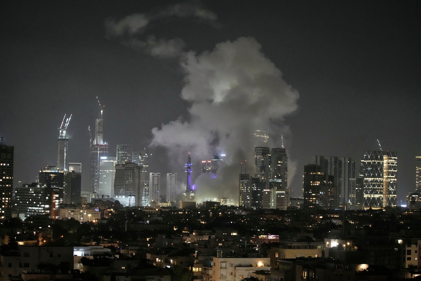 Smoke rises after a missile attack in Tel Aviv, Israel, Friday, June 13, 2025. (AP Photo/Leo Correa)