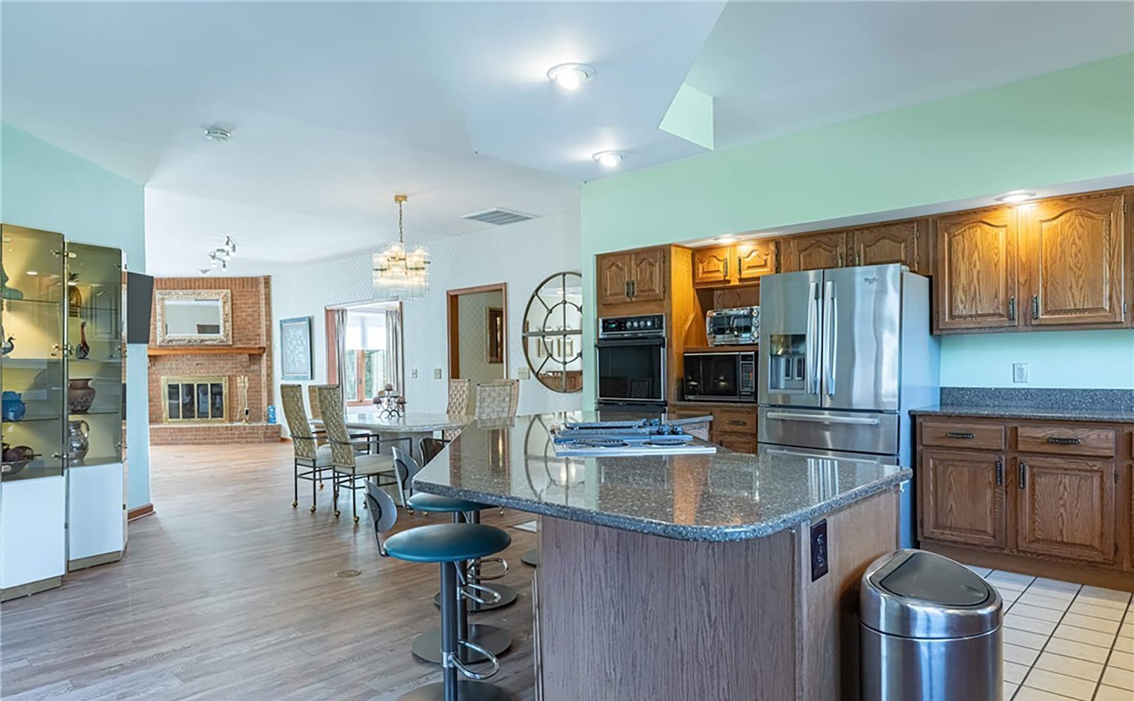 The open concept kitchen, living room and dining room has LVT flooring flowing throughout. There is a corner woodburning fireplace, wood cabinets with granite tops and recessed lighting. CONTRIBUTED