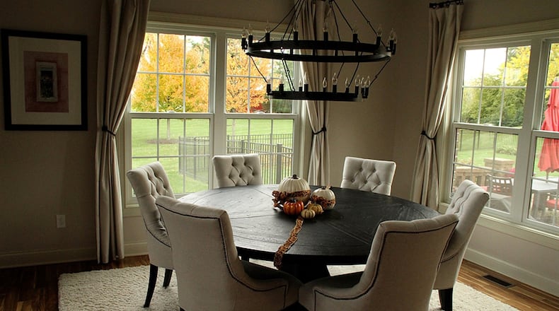 A large round wrought iron chandelier with multiple flame bulbs suggesting candles centers the dining room.