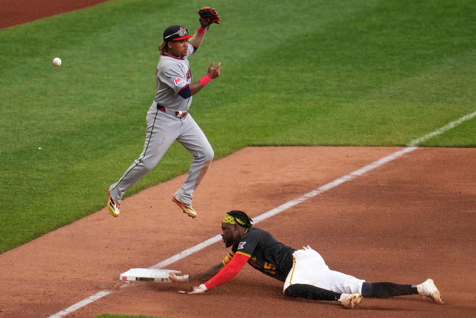 Pittsburgh Pirates' Oneil Cruz, right, slides safely into third as the ball gets past Cleveland Guardians third base José Ramírez during the sixth inning of a baseball game in Pittsburgh, Saturday, April 19, 2025. (AP Photo/Gene J. Puskar)