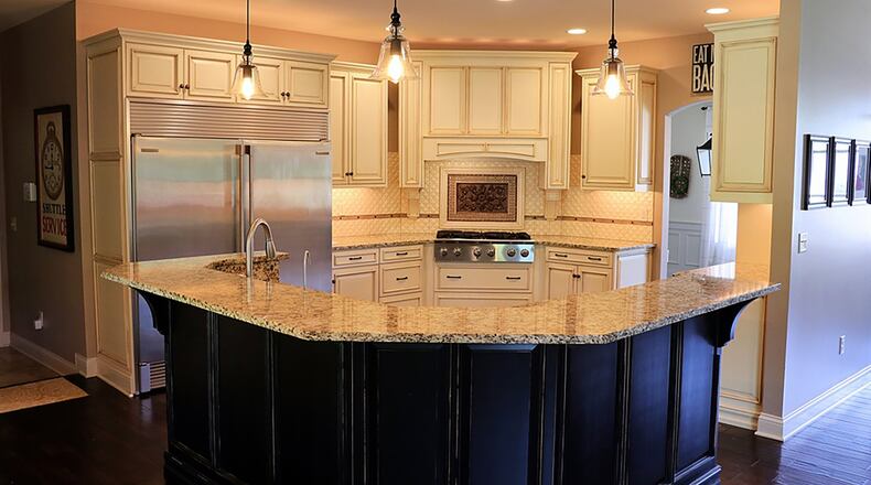 The kitchen features custom cabinetry, quilt-tile backsplash and a breakfast bar.