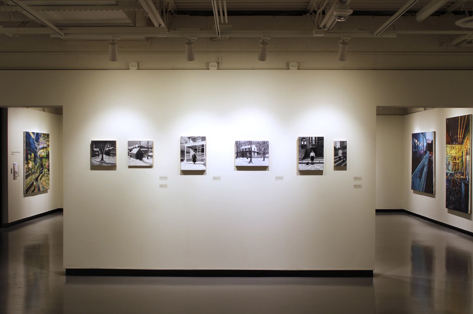 Kettering Health Art Gallery installation view of “Snow Light/Day and Night” by Kathy A. Moore, with paintings by Morgan Craig in background.