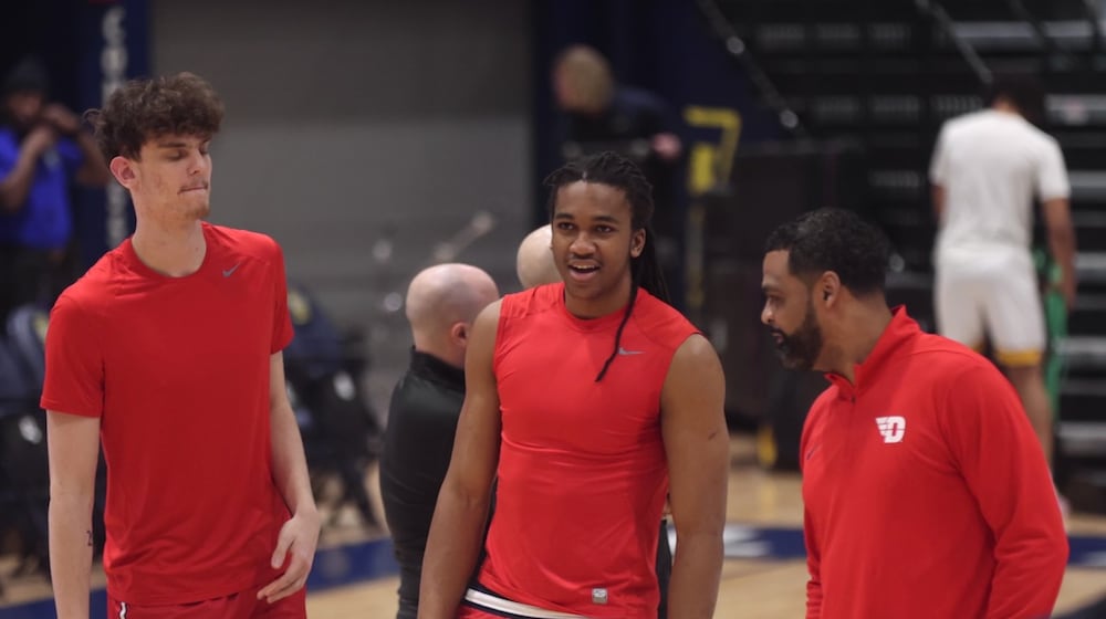 Dayton's Amaël L'Etang, left, and Malcolm Thomas, center, talk to Ricardo Greer before a game against La Salle on Wednesday, Jan. 21, 2026, at John E. Glaser Arena. David Jablonski/Staff