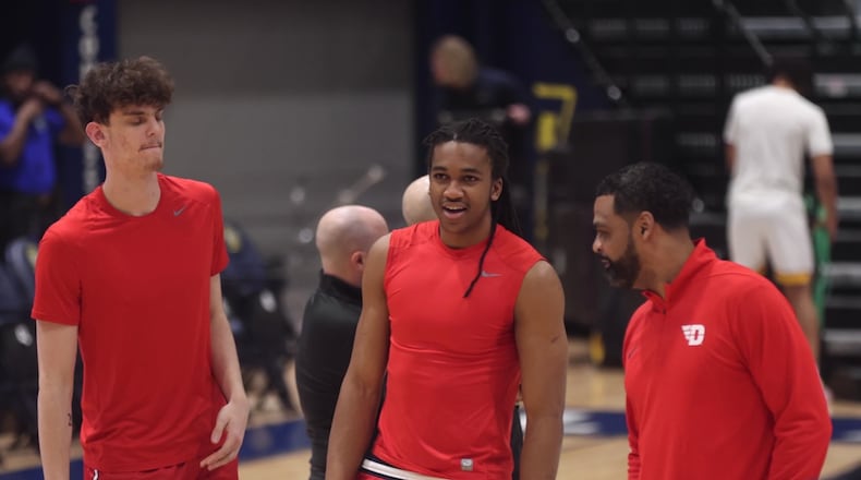 Dayton's Amaël L'Etang, left, and Malcolm Thomas, center, talk to Ricardo Greer before a game against La Salle on Wednesday, Jan. 21, 2026, at John E. Glaser Arena. David Jablonski/Staff