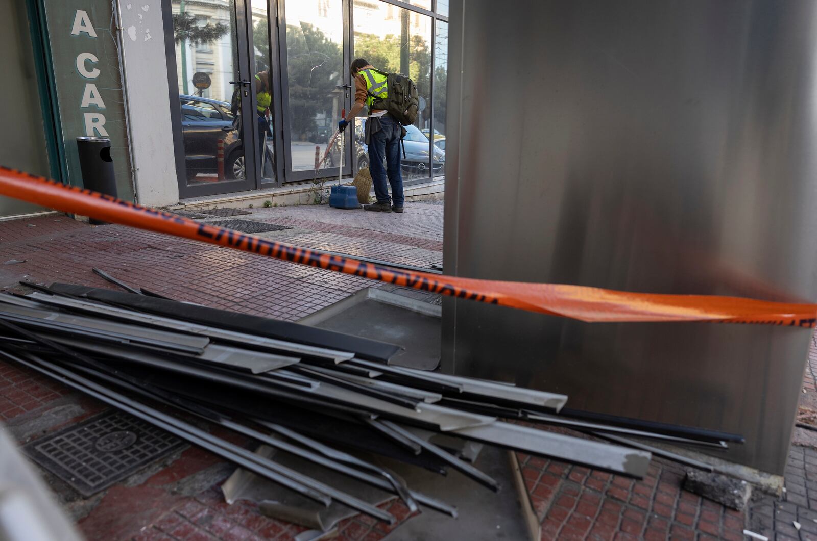 A municipal worker cleans the area outside Hellenic Train headquarters, Greece's main railway company, following a bomb explosion Friday night causing causing limited damage but no injuries, in Athens, Greece, on Saturday, April 12, 2025. (AP Photo/Yorgos Karahalis)