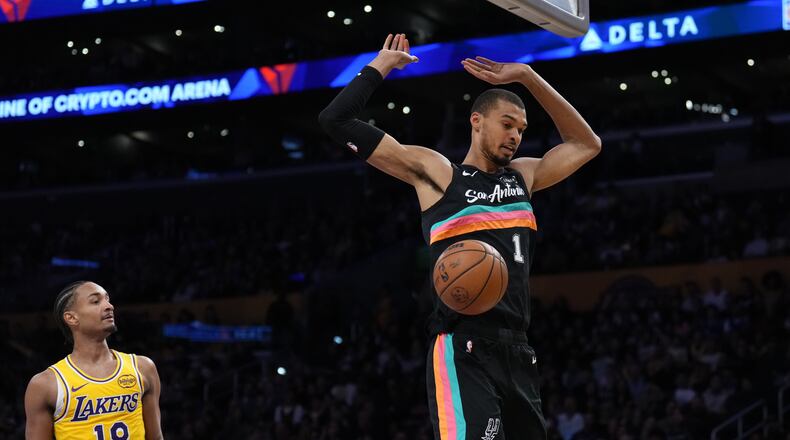 San Antonio Spurs forward Victor Wembanyama (1) descends after making a dunk as Los Angeles Lakers guard Kobe Bufkin (18) looks on during the first half of an NBA basketball game Tuesday, Feb. 10, 2026, in Los Angeles. (AP Photo/Jae C. Hong)