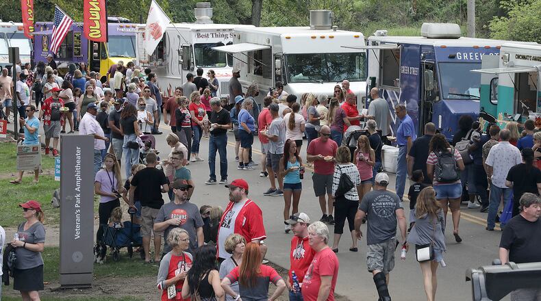 Hundreds of people walk up and down Cliff Park Drive eating from food trucks and watching Ohio State on a jumbotron screen Saturday during the Springfield Rotary Gourmet Food Truck Competition. BILL LACKEY/STAFF