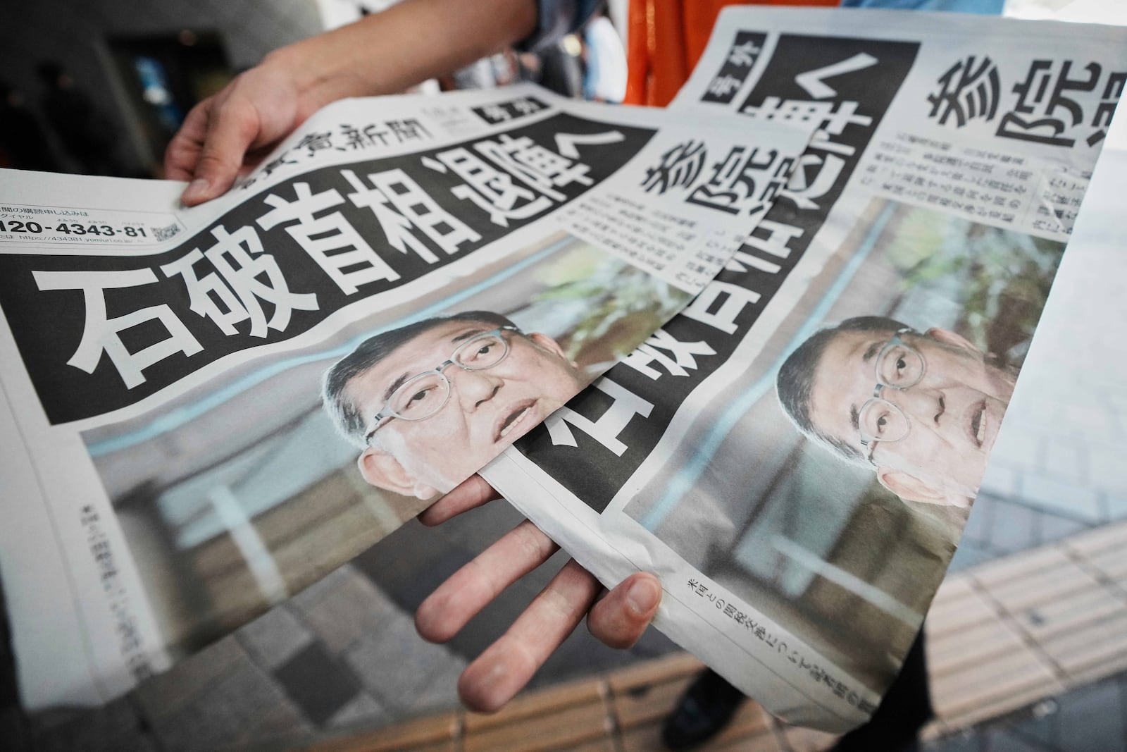 A staff member distributes an extra edition of the Yomiuri Shimbun newspaper, with headline reading "Prime Minister Ishiba towards resignation," Wednesday, July 23, 2025, in Tokyo. (AP Photo/Eugene Hoshiko)
