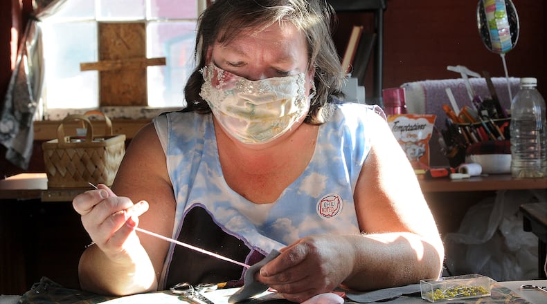 Liane Wagner, owner of Fairy Godmother Creations, hand sews hearts for a creation. MARSHALL GORBY / STAFF