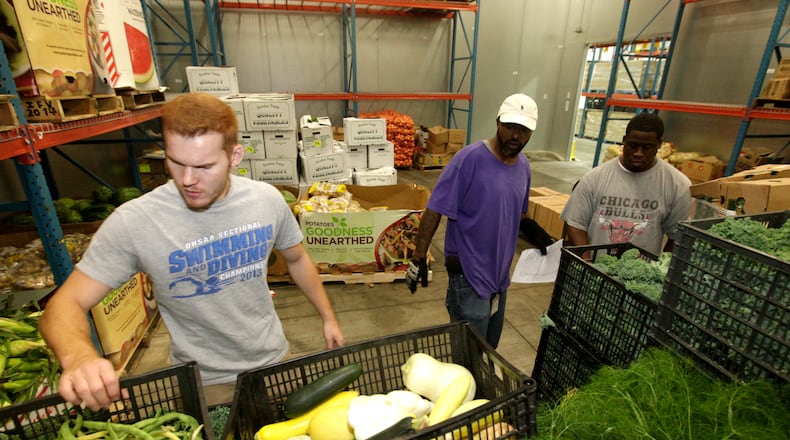 Cameron Rohrer, an employee of The Foodbank, Clark Brunson Jr., a volunteer and JaMichael Stallings, a Foodbank employee, (left to right) fill food orders to be picked up and distributed by area agencies Tuesday morning in Dayton. A new study shows that more than 70,000 people in Montgomery, Greene and Preble counties turn to food pantries and meal service programs to feed themselves and their families. LISA POWELL / STAFF PHOTO