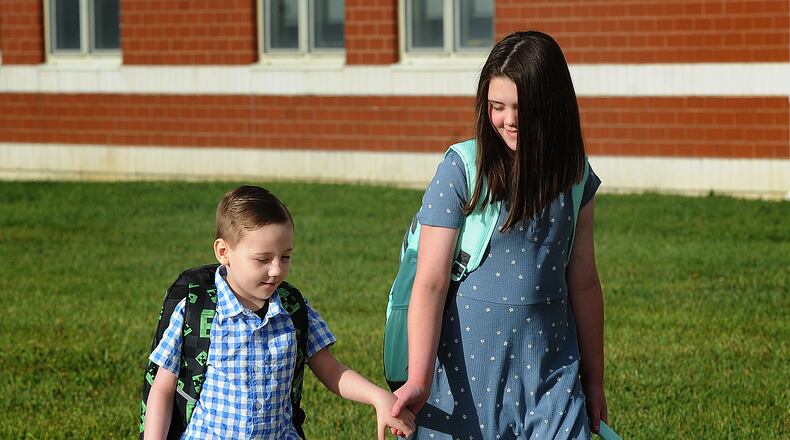 Leah Baker, age 9, walks with her brother Liam, age 5, to Jane Chance Elementary School in Miamisburg, Tuesday, Aug. 15, 2023, the first day on school.  MARSHALL GORY\STAFF