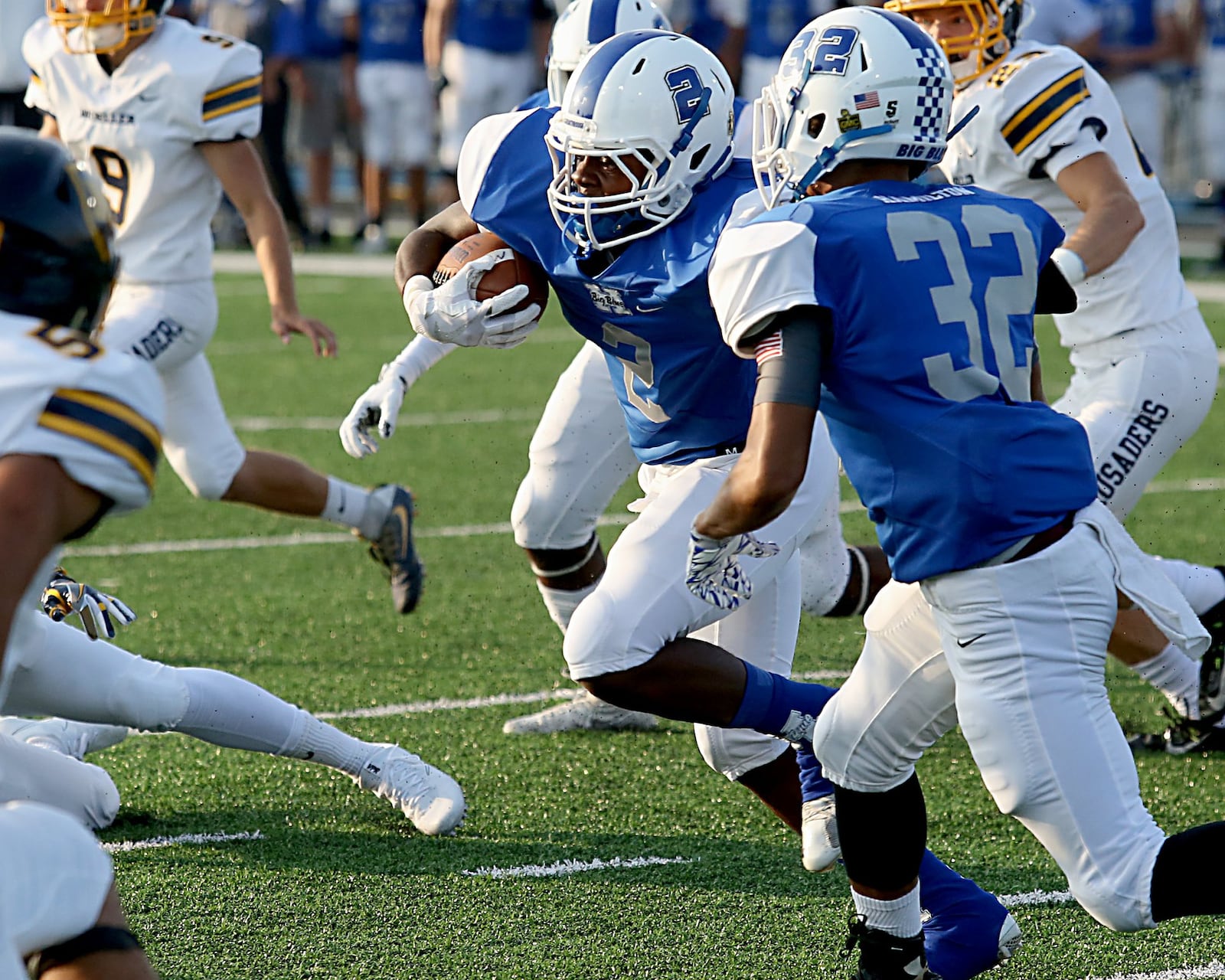 Hamilton’s DaQuan Maffett carries the ball in front of teammate Isaiah Harrison (32) during Saturday night’s Skyline Chili Crosstown Showdown game against Moeller at Virgil Schwarm Stadium in Hamilton. CONTRIBUTED PHOTO BY E.L. HUBBARD