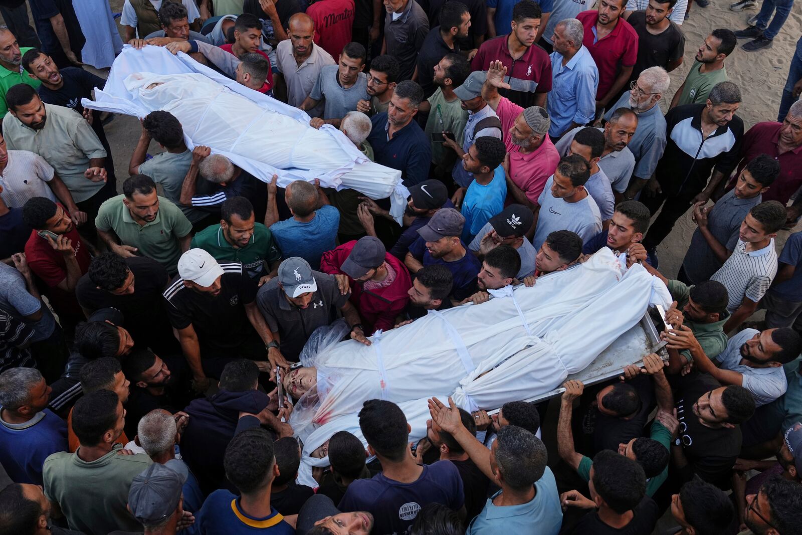 Palestinians carry the bodies of relatives who were killed in an Israeli military strike on Gaza, at Al-Shifa Hospital in Gaza City, Thursday, June 19, 2025. (AP Photo/Jehad Alshrafi)