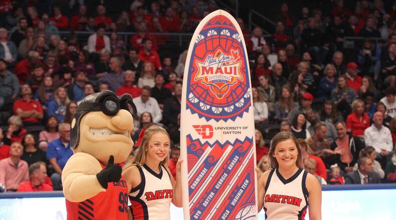 Dayton cheerleaders and Rudy Flyer show off a souvenir surfboard from the Maui Invitational at UD Arena during an exhibition game against Cedarville on Nov. 2, 2019.