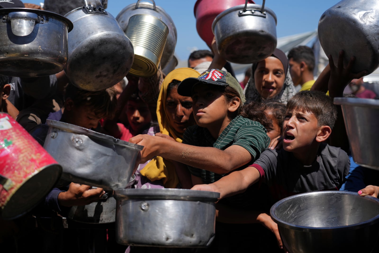 Palestinians struggle to get donated food at a community kitchen in Khan Younis, southern Gaza Strip, Monday, June 2, 2025. (AP Photo/Abdel Kareem Hana)