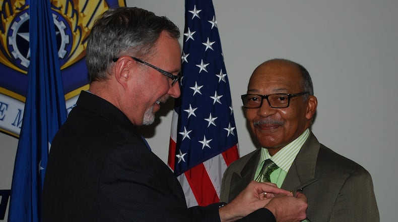 Thomas Doyon, director of the Air Force Materiel Command Law Office at Wright-Patterson Air Force Base, awards Fred Bennett Sr., a patent illustrator, with a gold pin commemorating 50 years of federal service Dec. 12 in Bldg. 11, Area B. (U.S. Air Force photo/Fred Rojas)