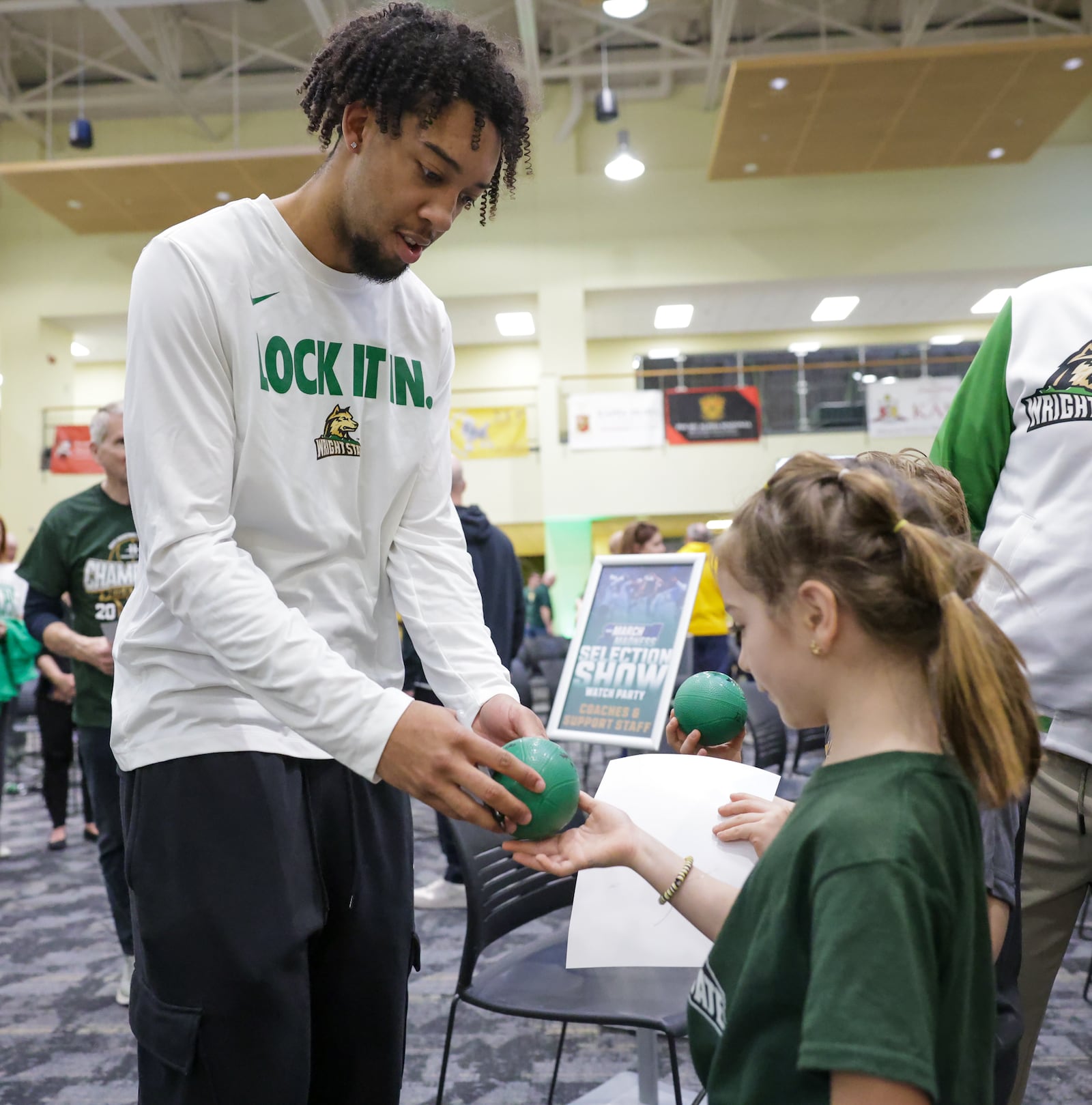 Wright State's Logan Woods signs autographs for a young fan at the team's NCAA tournament selection watch party on Sunday, March 15, 2026 at the university's Student Union in Fairborn. BRYANT BILLING / STAFF
