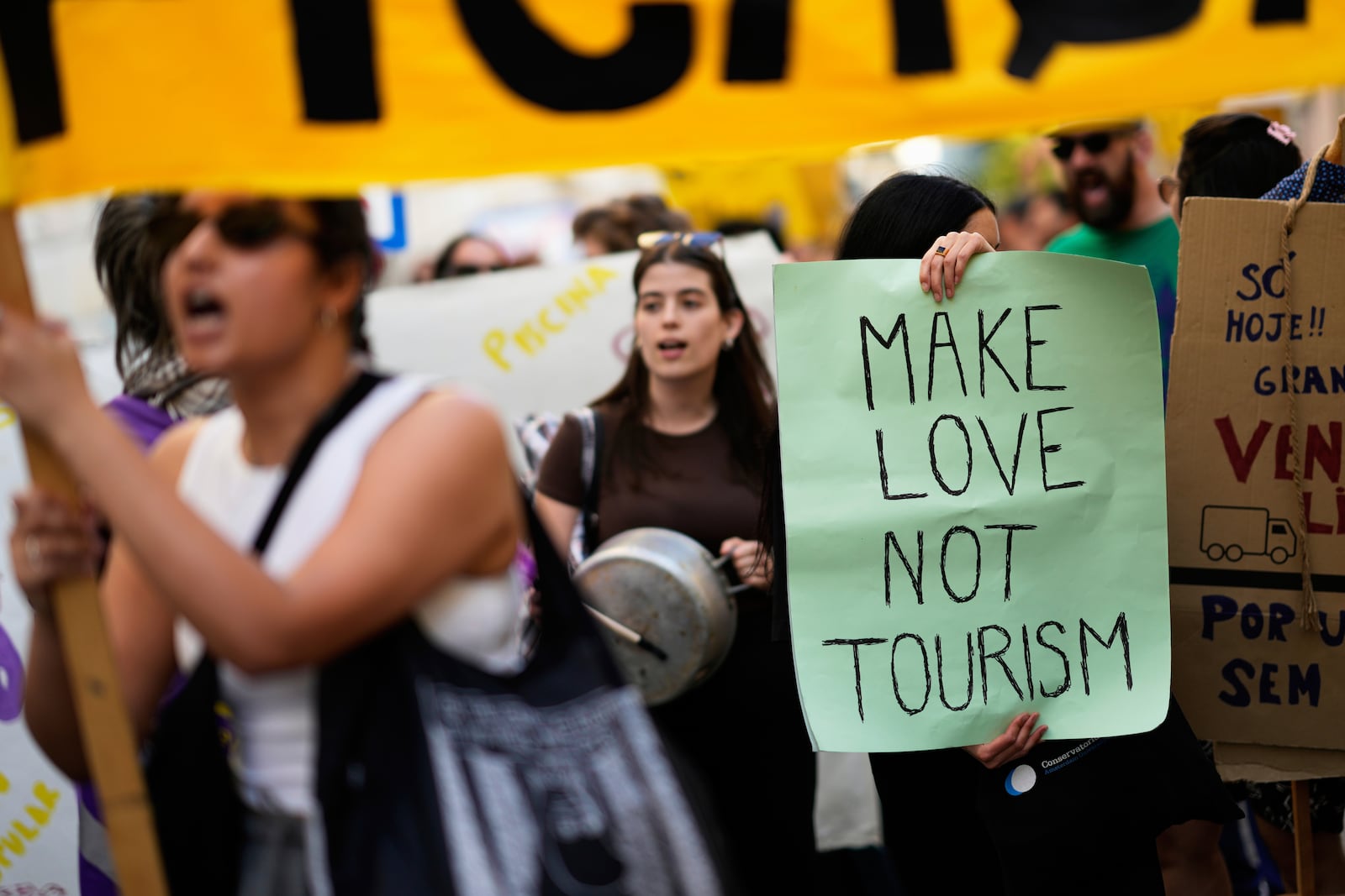 Demonstrators bang pots and shout slogans during a protest against mass tourism in Lisbon, Sunday, June 15, 2025. (AP Photo/Armando Franca)