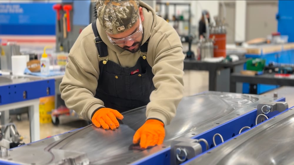 A Joby Aviation employee polishes a large metal mold inside the company’s new aircraft blade manufacturing facility near Dayton International Airport.