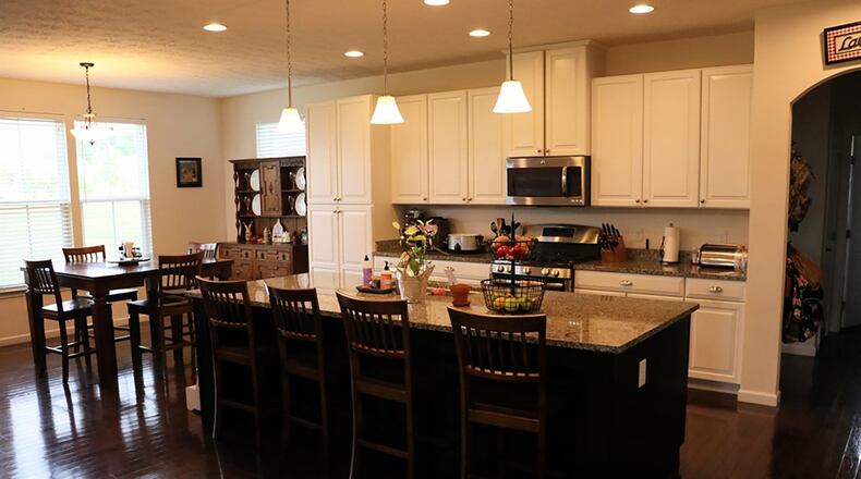 In the kitchen, a long wide center island topped with granite facilitates bar seating on the outer side. The double sink with a telescopic faucet and a stainless-steel dishwasher are installed on the island’s inner side, creating an easy-flow, galley-style workspace.